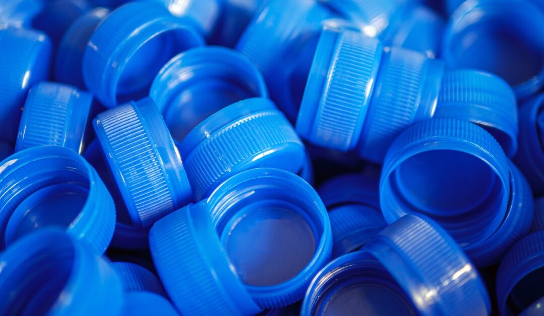 A close-up of blue bottle caps with a screw-cap function. They are all the same shade of blue scattered in a pile.