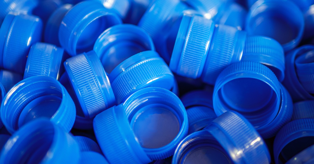 A close-up of blue bottle caps with a screw-cap function. They are all the same shade of blue scattered in a pile.