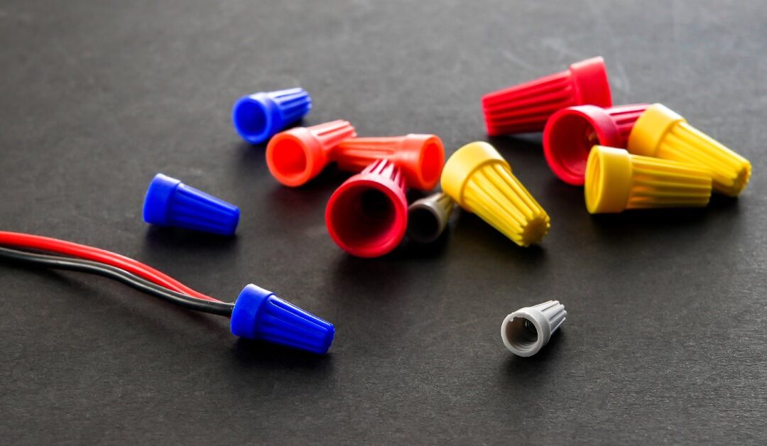 Colorful connection caps that vary in size. There are red and black wires attached to a blue connection cover.